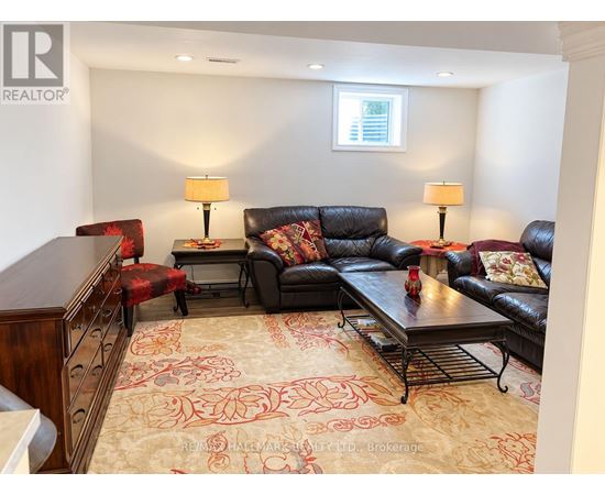 A living room with a black couch and a rug with a red pattern.