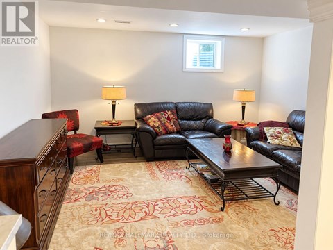 A living room with a black couch and a rug with a red pattern.