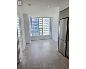 A spacious kitchen with a refrigerator and a view of a high-rise building outside the window.