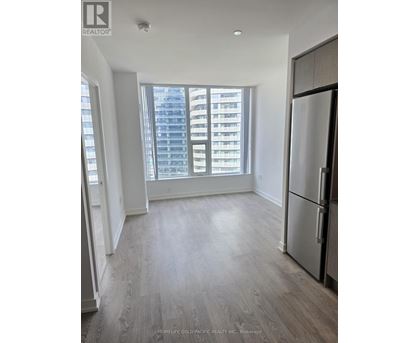 A spacious kitchen with a refrigerator and a view of a high-rise building outside the window.