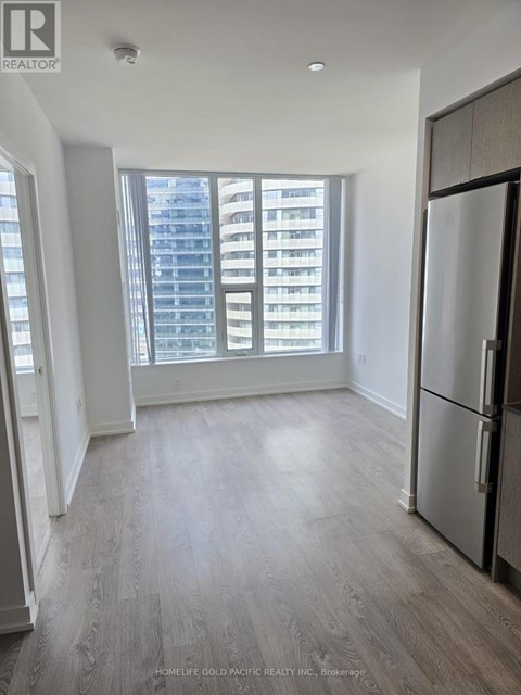 A spacious kitchen with a refrigerator and a view of a high-rise building outside the window.