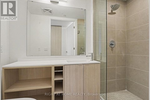 A bathroom with a sink, mirror, and shower.
