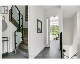 A modern interior space with a glass staircase and a painting on the wall.