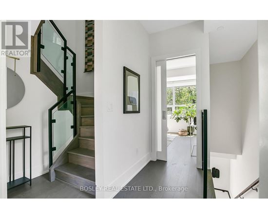 A modern interior space with a glass staircase and a painting on the wall.