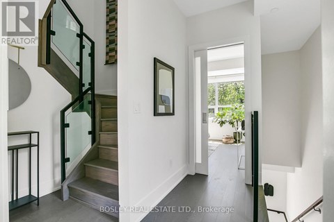 A modern interior space with a glass staircase and a painting on the wall.