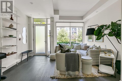 A modern living room with a large window and a view of trees outside.