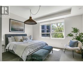 A bedroom with a large bed and a hanging lamp.