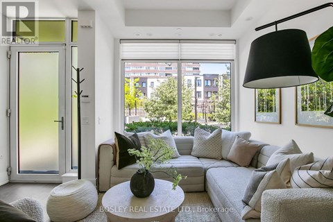 A living room with a grey couch, a white coffee table, and a large window with a view of the city.