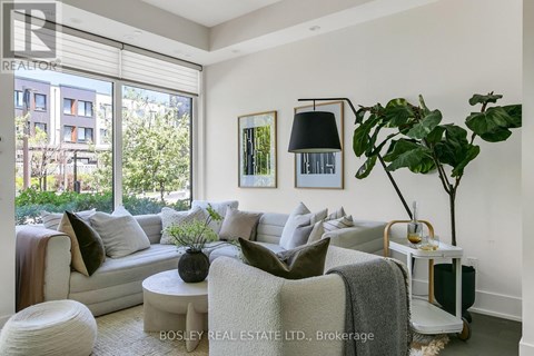 A living room with a large window, a white couch, and a potted plant.
