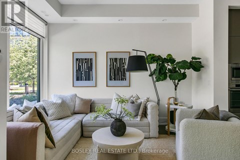A living room with a white couch, a coffee table, and a large window.