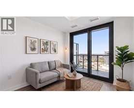 A living room with a grey couch, a coffee table, and a large window with a view of the city.