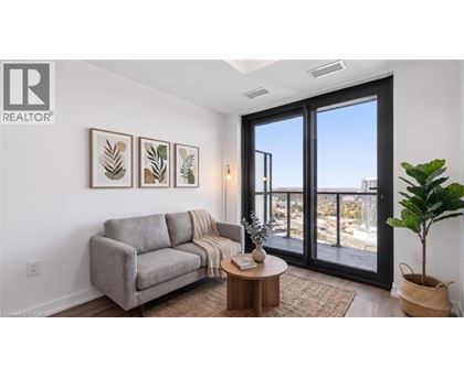 A living room with a grey couch, a coffee table, and a large window with a view of the city.