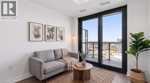 A living room with a grey couch, a coffee table, and a large window with a view of the city.
