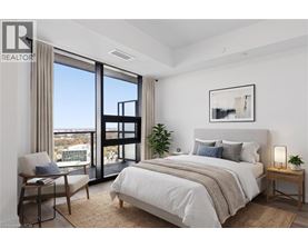 A bedroom with a large bed, a chair, and a view of the city.