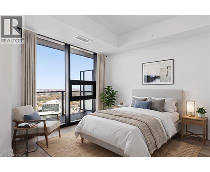 A bedroom with a large bed, a chair, and a view of the city.
