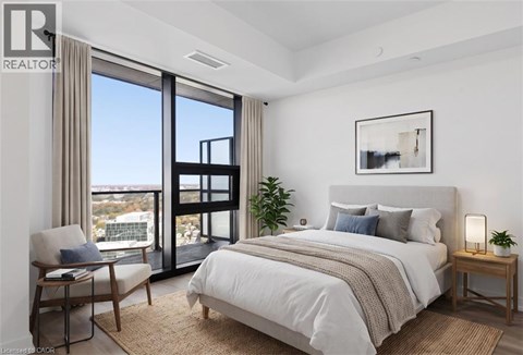 A bedroom with a large bed, a chair, and a view of the city.