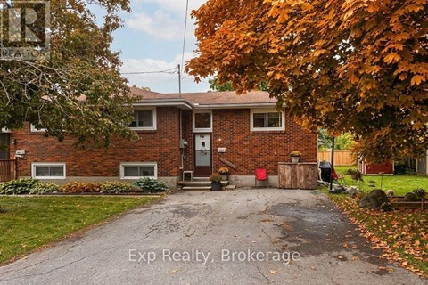 A house with a driveway and a tree with orange leaves.