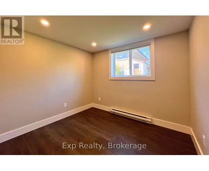A room with a window and wooden flooring is available for exp realty.