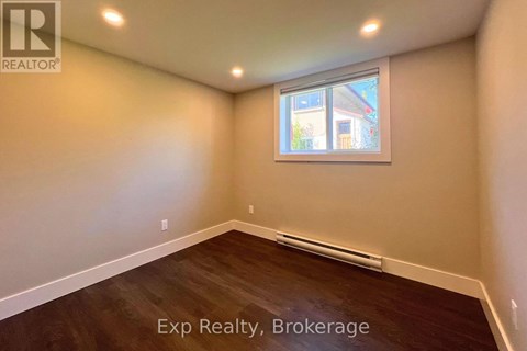 A room with a window and wooden flooring is available for exp realty.