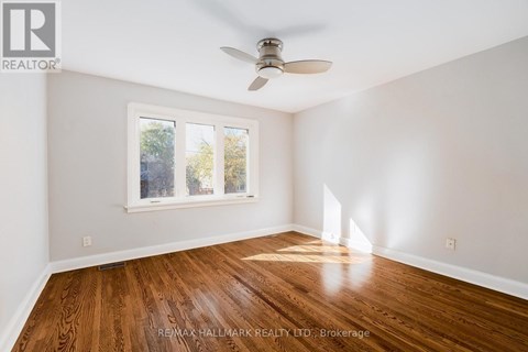 A room with a ceiling fan and a window with a view of trees.