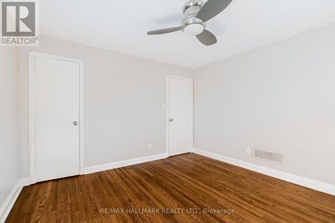 A room with a ceiling fan and wood flooring.