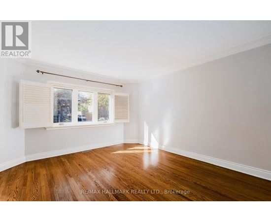 A room with wooden floors and a window with blinds.