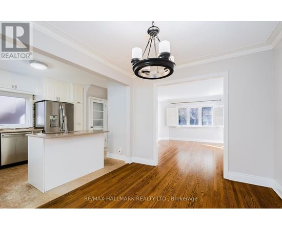 A well-lit kitchen with white cabinets and a wooden floor.
