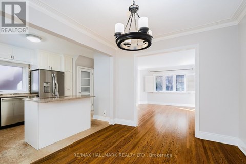 A well-lit kitchen with white cabinets and a wooden floor.