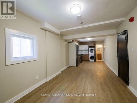 A spacious room with wooden floors and a large window.