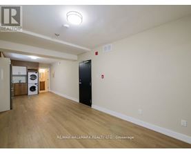 A spacious room with a black door and a washer and dryer in the corner.