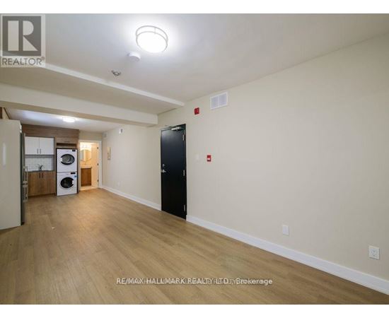 A spacious room with a black door and a washer and dryer in the corner.
