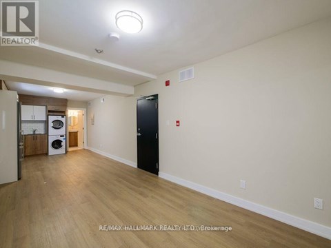 A spacious room with a black door and a washer and dryer in the corner.