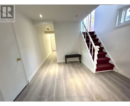 A hallway with a red carpeted staircase and a bench.