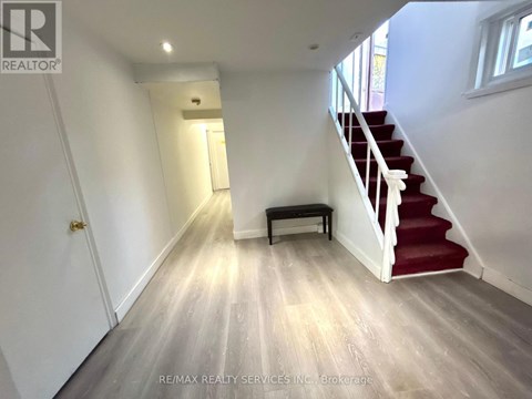 A hallway with a red carpeted staircase and a bench.