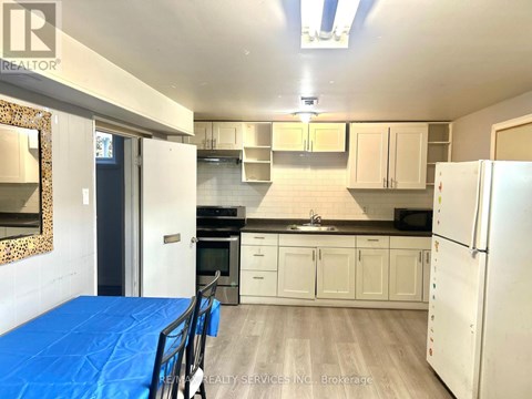 A kitchen with white cabinets and a blue tarp on the floor.