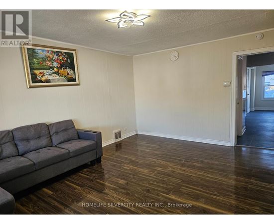 A living room with a grey couch and a painting on the wall.