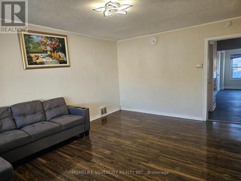 A living room with a grey couch and a painting on the wall.