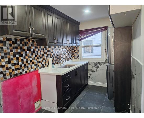 A kitchen with black cabinets and a checkered backsplash.