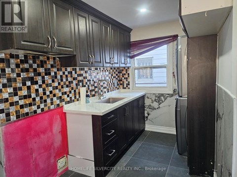 A kitchen with black cabinets and a checkered backsplash.