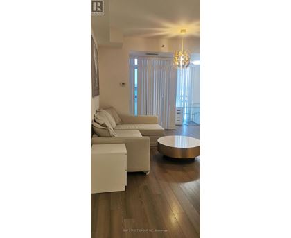 A living room with a white couch and a wooden floor.
