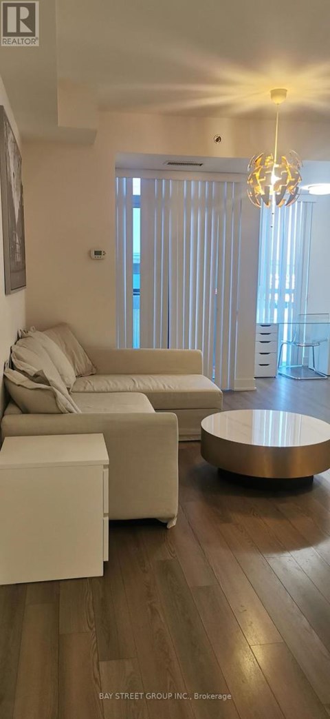 A living room with a white couch and a wooden floor.