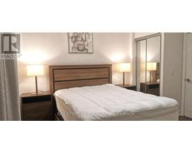 A bedroom with a bed, two nightstands with lamps, and a painting on the wall.