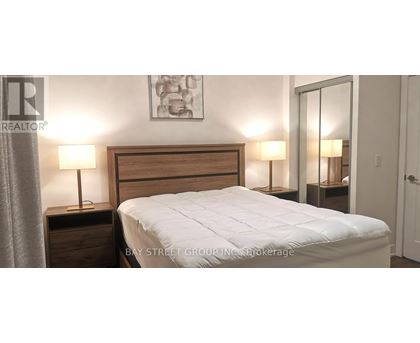 A bedroom with a bed, two nightstands with lamps, and a painting on the wall.