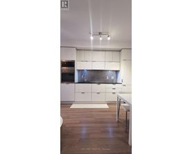 A modern kitchen with white cabinets and a wooden floor.