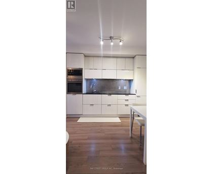 A modern kitchen with white cabinets and a wooden floor.