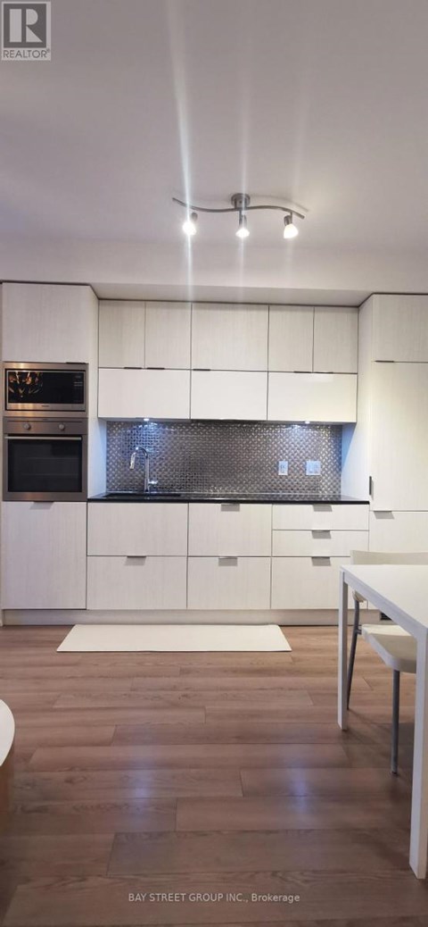 A modern kitchen with white cabinets and a wooden floor.