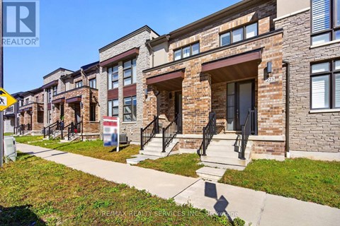A row of townhouses with a REALTOR® sign in front.