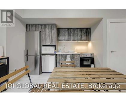 A kitchen with a refrigerator, oven, and a wooden table.