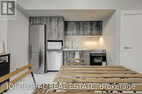 A kitchen with a refrigerator, oven, and a wooden table.