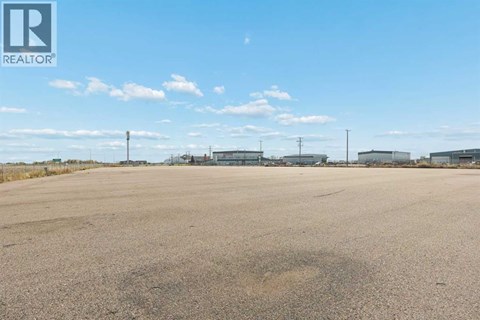 A large, empty parking lot with a clear blue sky above.